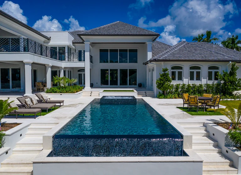 Long rectangular pool in front of a luxury Florida residence