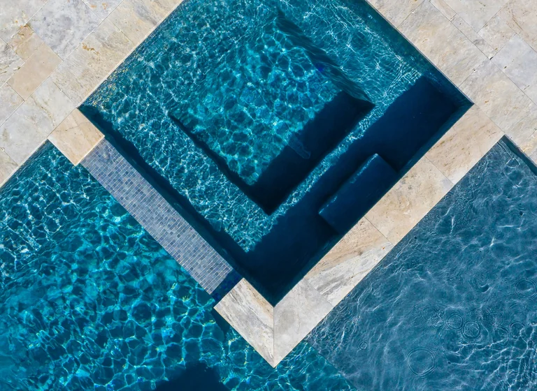 Overhead view of a geometric pool and spa framed in stone coping