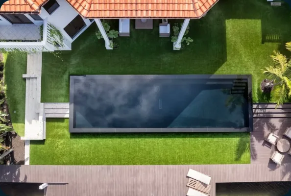Aerial view of a dark rectangular pool beside a Florida home